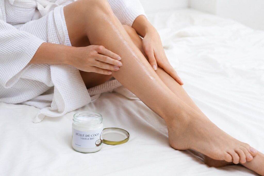 femme applicant de l'huile de coco sur ses jambes